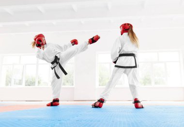 Özel kırmızı koruyucu eldiven ve kask ile mücadele için ayakkabı giyiyor, karate tekniği tekme ve yumruk boks genç kadın savaşçı. İki kız eğitim karate beceri özel sınıf birlikte.