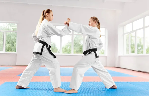 Duas meninas atléticas lutando usando técnicas de karatê na classe de karatê leve . — Fotografia de Stock