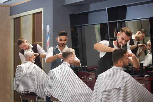 Три профессиональных парикмахера обрезка, стрижка и укладка волос клиентов мужского пола . — стоковое фото