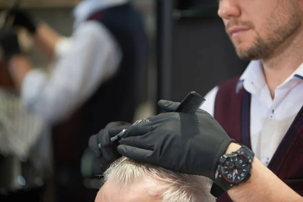 Barbier méconnaissable couper les cheveux de son client dans le salon de coiffure — Photo