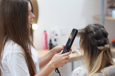 Düzleştiriciyi yapmak için uygulayarak Kuaför Güzellik Salonu müşteriye bukleler