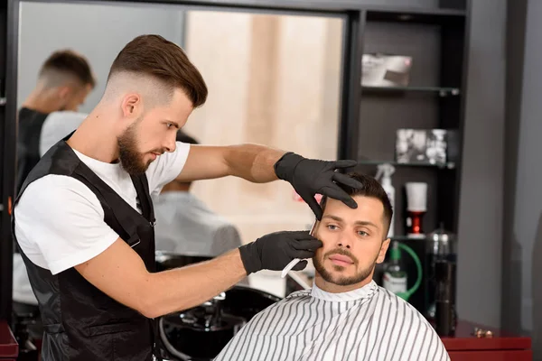 Selbstbewusst Friseur rasiert Kunden Bart mit scharfem Rasiermesser. — Stockfoto