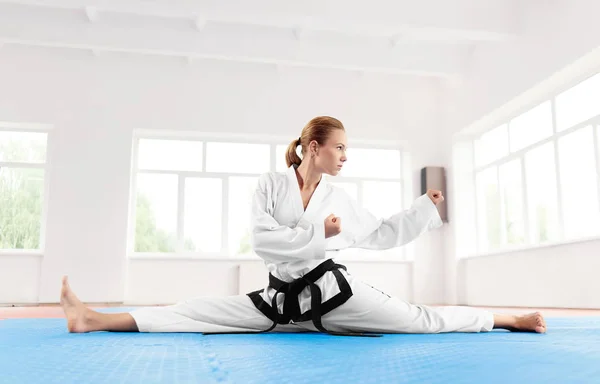 Karatê mulher, vestindo em quimono alongamento perna antes do treino duro . — Fotografia de Stock