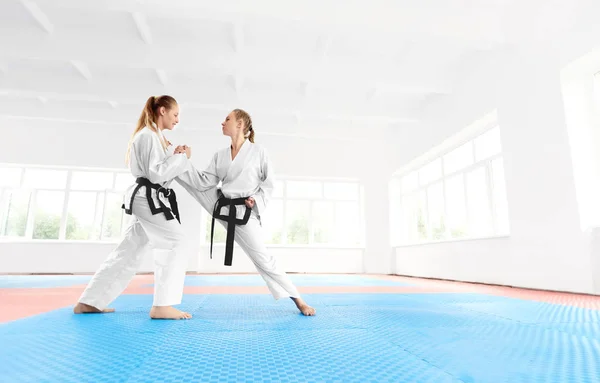 Jovem Karate menina ajudando a sua parceira alongamento perna antes do treinamento . — Fotografia de Stock