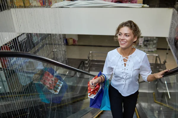 Front view of female customer driving up on escalator in mall