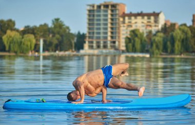 Handstanding pozisyon kürek tahta üzerinde sıcak yaz günü sırasında yapıyor oğlan.