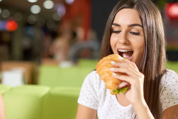 Hungrige Frau beißt in Café auf Croissant — Stockfoto