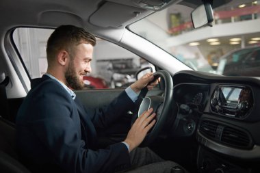 Araba tutmak içinde oturan adam direksiyon simidi üzerinde eller.