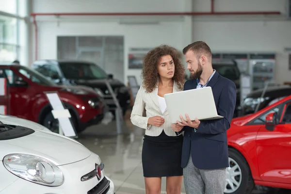 Správce autodům znázorňující automobil k ženě. — Stock fotografie