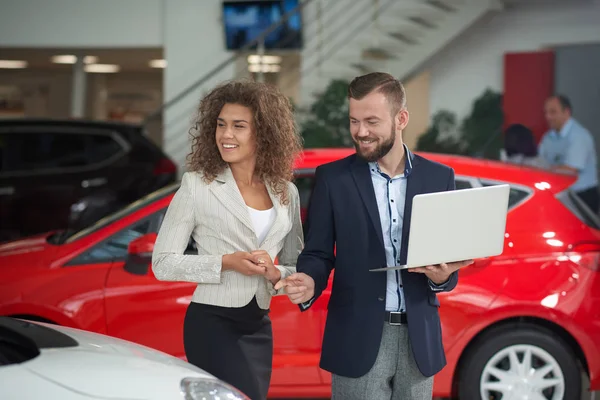 Femme heureuse de choisir la voiture avec le gestionnaire de concessionnaire automobile . — Photo