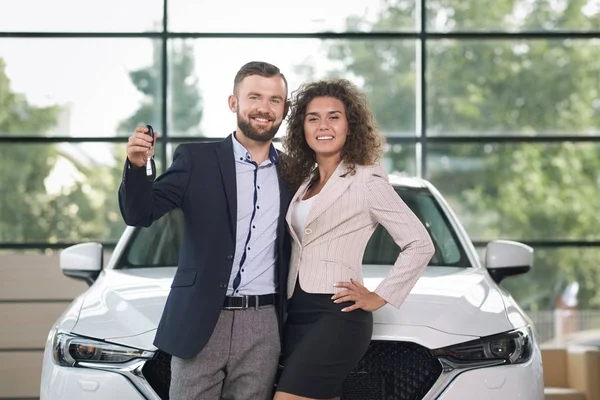 Usmívající se pár stojící poblíž bílé auto, při pohledu na fotoaparát. — Stock fotografie