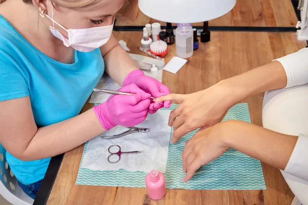 Manicurist in process of doing manicure to female customer in beauty salon. — Stock Photo, Image