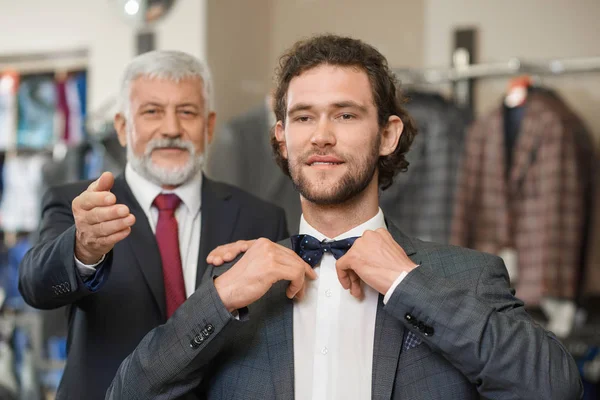 Two happy atractive elegant men choosing clothes for special occaision.