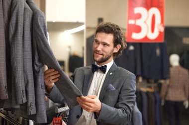 Gri kostümlü ceket tutan genç çekici damat.