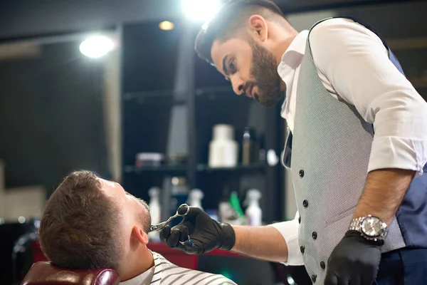 View from side of stylish barber cutting beard of male — Stock Photo, Image