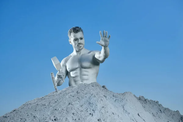 Stříbrný muž z kamene mezi šedivým pískem ukazující ruka. — Stock fotografie