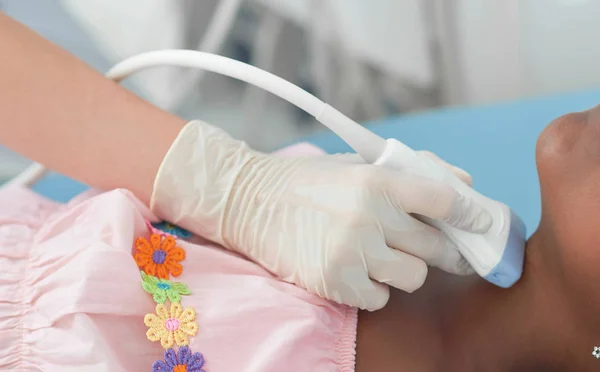 Primer plano del médico escaneo de la mano cuello de la niña afro . — Foto de Stock