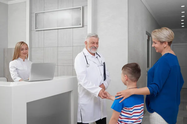 Doctor estrechando la mano con chico en consulta . —  Fotos de Stock