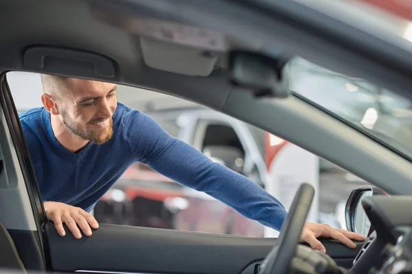 Stilig man i blå tröja tittar på utformningen av bilen. — Stockfoto