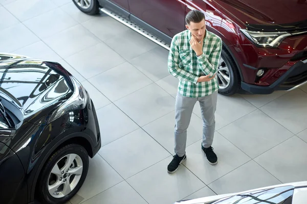 Joven parado entre coches negros y rojos oscuros . —  Fotos de Stock