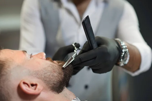 Закрытие процесса обрезки бороды клиента в парикмахерской — стоковое фото