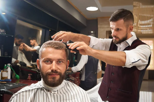 Мужчина, сидящий на стуле в парикмахерской в процессе стрижки — стоковое фото