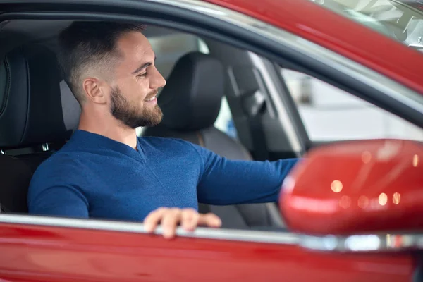 Cliente atractivo en suéter azul eligiendo auto en el salón . — Foto de Stock