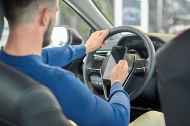 Adam ön koltuk oturma ve smartphone kullanarak kırpma.