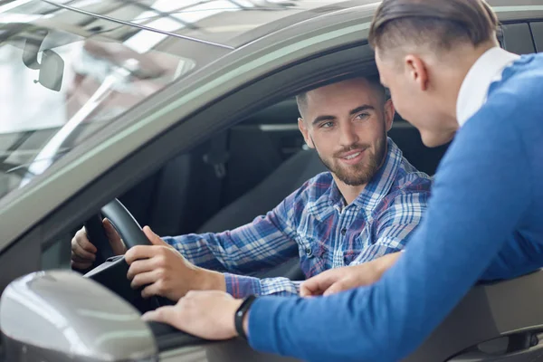 Ung man i blå tröja att hjälpa sin vän att välja auto. — Stockfoto