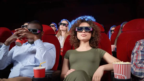 Afro man and curled brunette sitting in cinema. — Stock Photo, Image