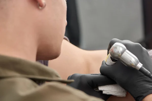 Young guy holding machine painting on naked body. — Stock Photo, Image