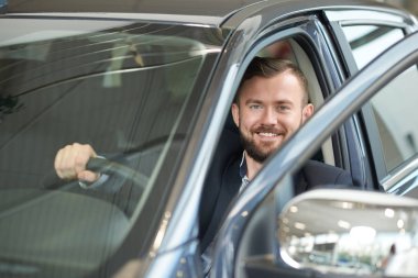 Yakışıklı adam arabanın içinde poz.