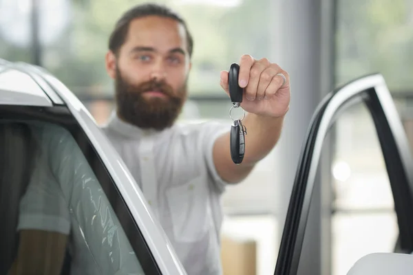 Homme tenant des clés de voiture dans la salle d'exposition de voiture . — Photo