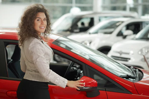 Linda mulher posando perto de carro vermelho no centro do carro . — Fotografia de Stock