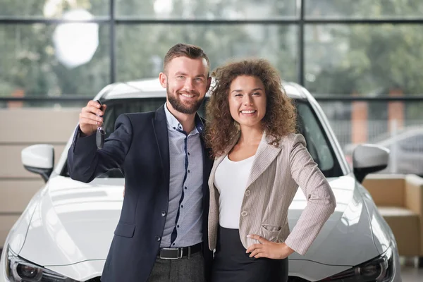 Pareja feliz posando con nuevo coche blanco y llaves . —  Fotos de Stock