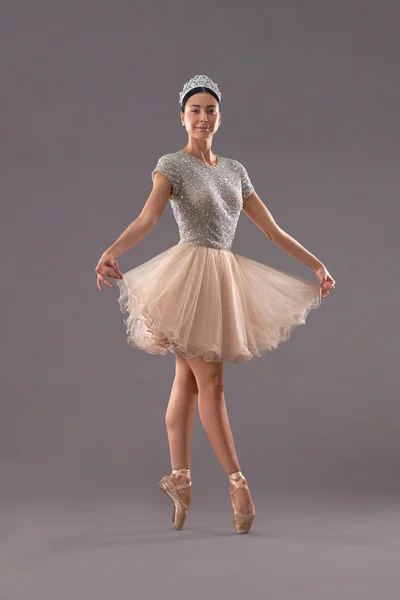 Vue de face de la ballerine gardant robe avec les doigts en studio — Photo