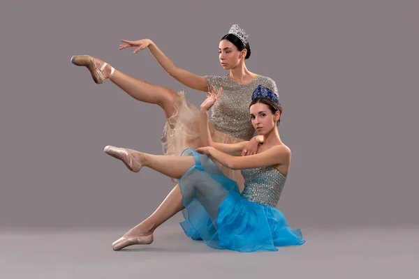 Two beautiful ballerinas sitting in studio and posing