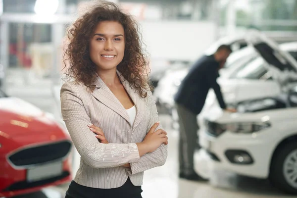 Mulher bonita posando, sorrindo no showroom do carro . — Fotografia de Stock