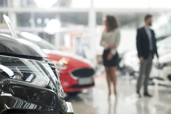 Auto světlometů a lidé pozorovat automobilů v showroomu. — Stock fotografie