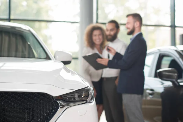 Prodejce automobilů s klienty o nákupu vozu. — Stock fotografie