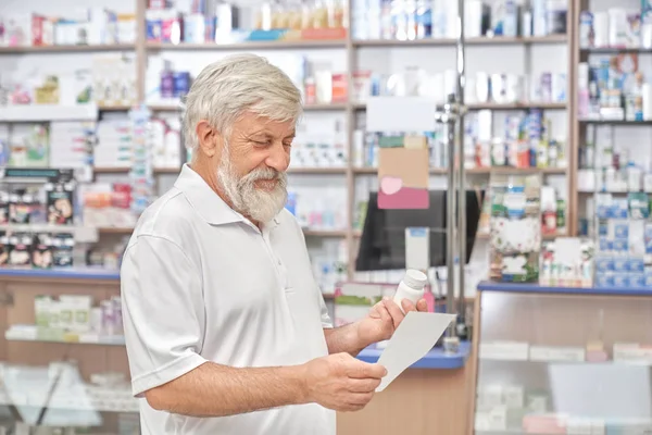 Pensionista mirando prescripción en farmacia . — Foto de Stock