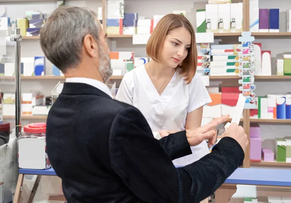 Cliente che mostra al farmacista prescrizione in farmacia . — Foto Stock