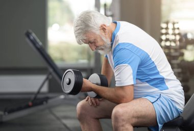 Yaşlı adam spor salonunda dumbbells ile çalışma dışarı uygun.