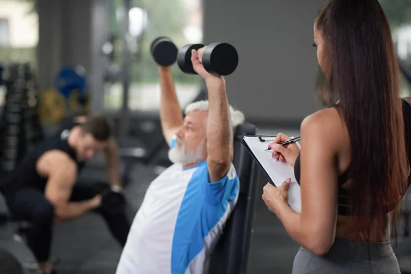 Treinamento de homem mais velho com mulher no ginásio . — Fotografia de Stock