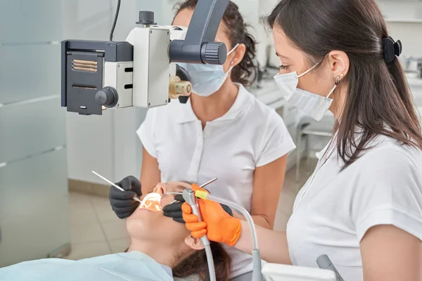 Paciente acostado en la silla dental mientras el dentista trata los dientes — Foto de Stock