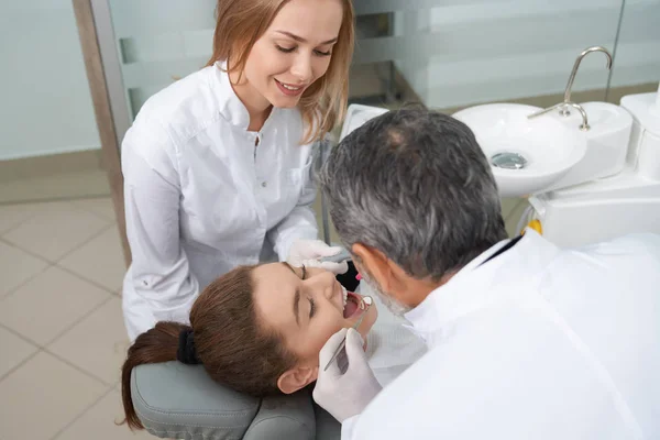 Paciente femenina con boca abierta y dentista revisando dientes — Foto de Stock