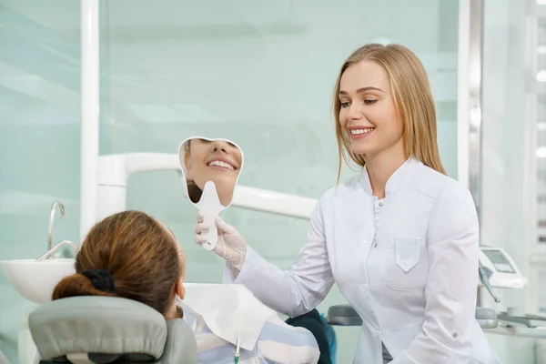 Dentista manteniendo espejo y mostrando al cliente una hermosa sonrisa —  Fotos de Stock