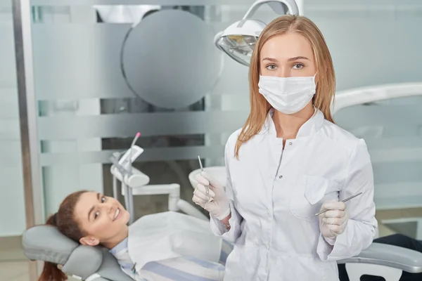 Dentista em máscara médica posando com o paciente . — Fotografia de Stock