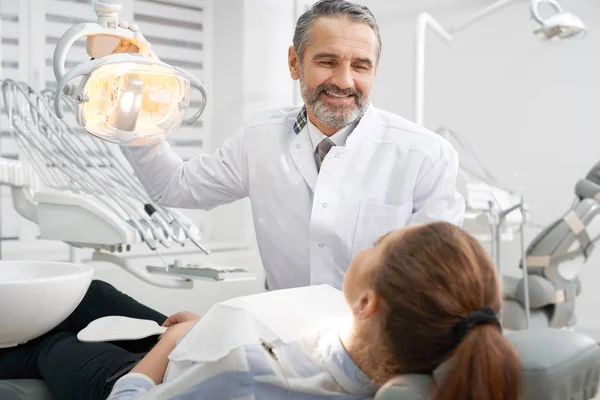 Cheerul dentista sorrindo, olhando para o paciente . — Fotografia de Stock