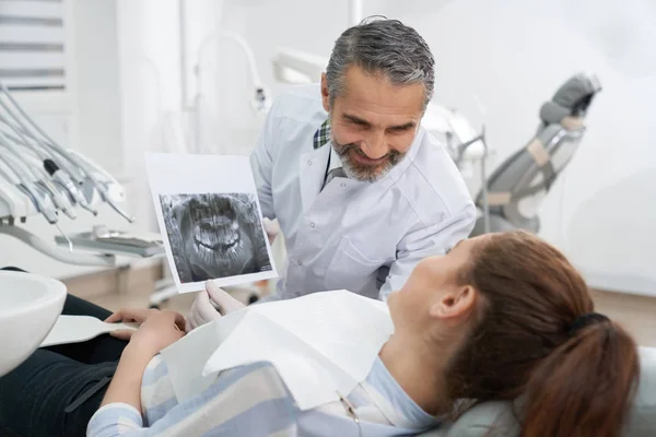 Dentista consultando al paciente sobre radiografía dental . — Foto de Stock